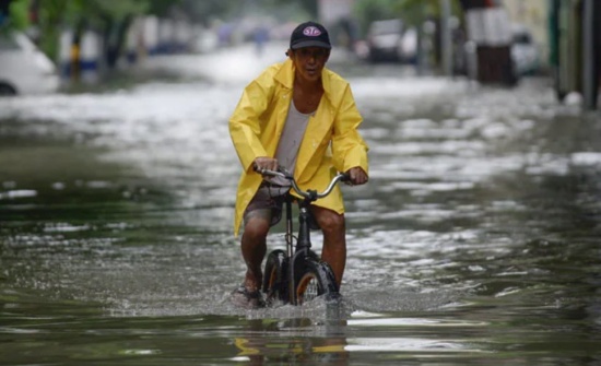 菲律賓暴雨，馬尼拉洪澇災害，一名騎自行車的男子涉水穿過被洪水淹沒的街道。
